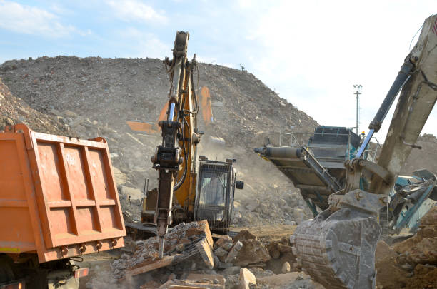 Salvaging and recycling building and construction materials. Industrial waste treatment plant. Excavator work at landfill with concrete demolition waste. Re-use concrete for new construction salvar y reciclar materiales de construcción y construcción de edificios. planta de tratamiento de residuos industriales. trabajo de excavadora en vertederos con residuos de demolición de hormigón. reutilizar hormigón para nueva construcción