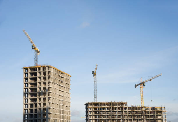 istock Tower cranes constructing a new residential building at a construction site against blue sky 1210606196
