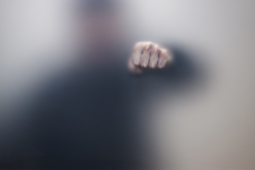 Male fist behind matte glass wall, abstract photo