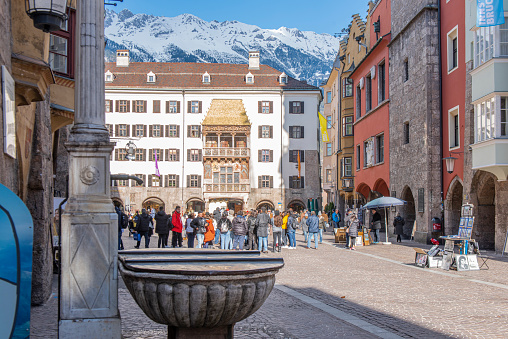 People walking next to the Goldenes Dachl (Golden Roof) in a pedestrian street at Innsbruck old town, Austria. Located in the Inn valley in the Austrian Alps and capital of Tyrol,  it is one of the most important winter sports city in the world.