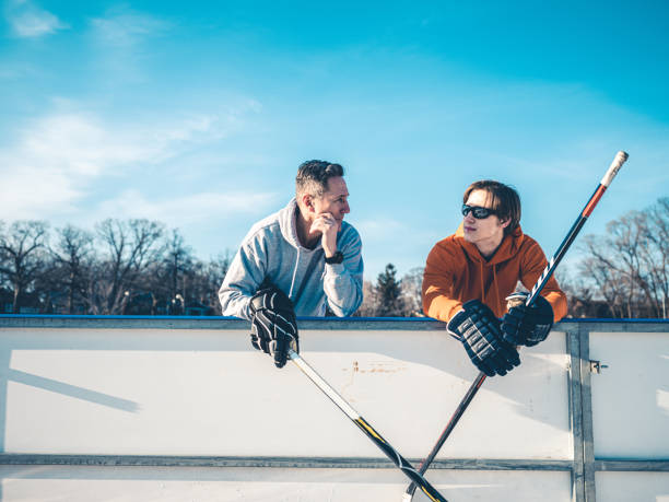 vater und sohn spielen hockey im freien - ice skating ice hockey child family stock-fotos und bilder