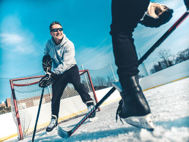 vater und sohn spielen hockey im freien - ice skating ice hockey child family stock-fotos und bilder