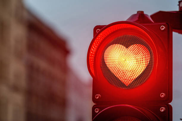 una città che attraversa con un semaforo, semaforo a forma di cuore rosso in semaforo - romanticismo concetto foto e immagini stock