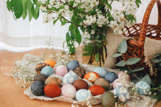 istock Easter eggs on rustic background with basket, spring flowers and green branches, rural still life. Stylish colorful Easter eggs with modern ornaments painted with natural dye. Zero waste 1210614805