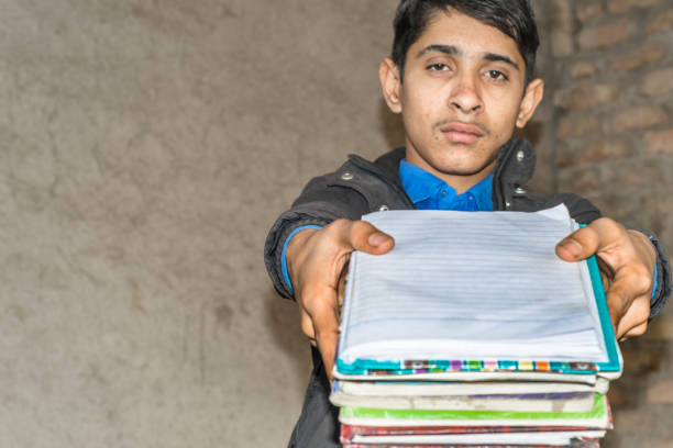 istock a young student wearing school uniform is offering books as charity purpose 1210620600