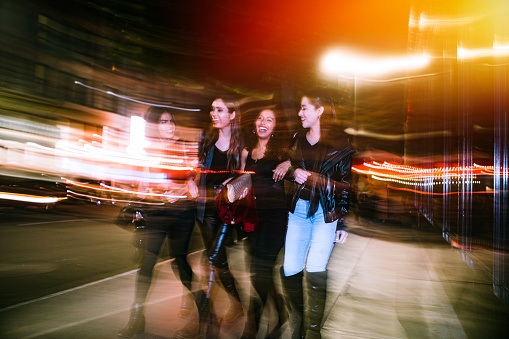 A group of young Hispanic women enjoy an evening out on the town in downtown Los Angeles, California.  They walk the streets of downtown LA, having a fun time.  Long exposure with blurred motion.