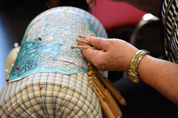 The old craft technique of lace making - Bobbin lace making is a manual technique in which various types of lace are made using a bobbin (spindle-shaped, mostly made of wood \