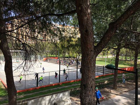 Valencia, Spain - February 29, 2020: Group of people playing soccer in one of the many fields that can be found along the Turia Garden. This is an old riverbed converted into a verdant sunken park that many people use to exercise, play sports and have fun