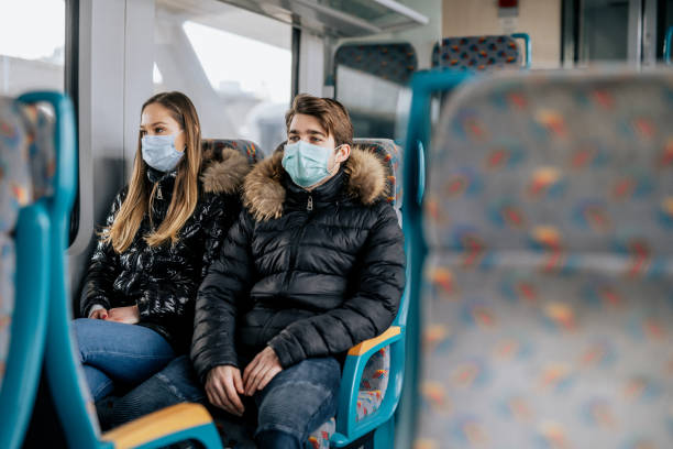 istock Young couple is sitting on a train wearing protective face masks 1210625797