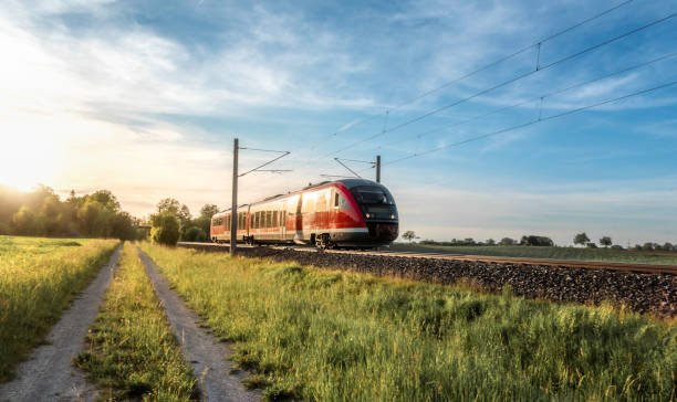 Passenger train on sunny day of summer in Germany German train traveling through green fields on a sunny day of summer. Passenger train on rail tracks at sunset. passenger train photos stock pictures, royalty-free photos & images