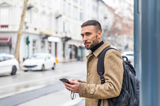 Handsome Tourist Wearing a Coat and Holding Mobile Phone in Italy - Stock Photo