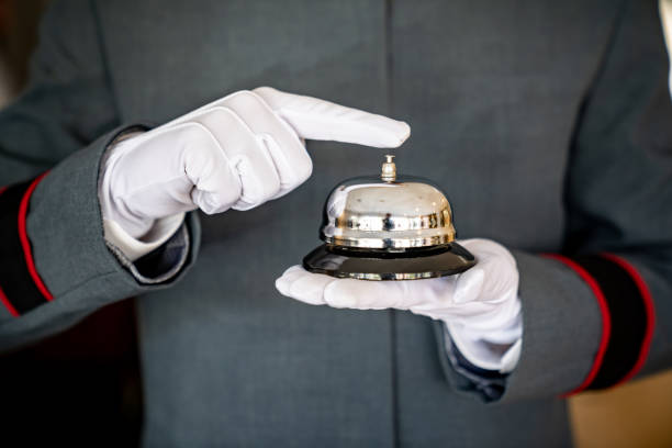 Close-up on a bell boy working at a hotel holding a service bell