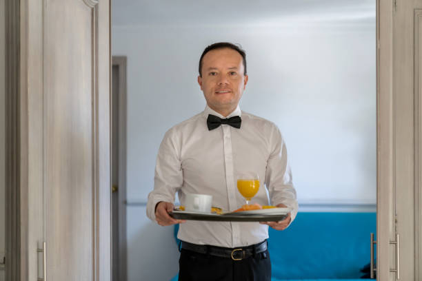 istock Happy concierge bringing room service to a room at a hotel 1210628873