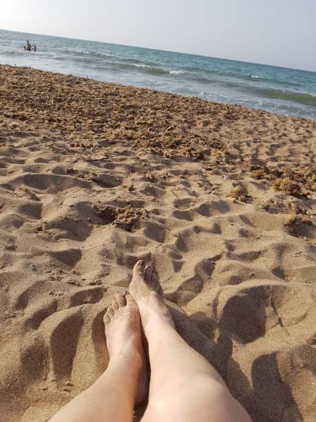 istock WITH LEGS IN THE SAND 1210630391