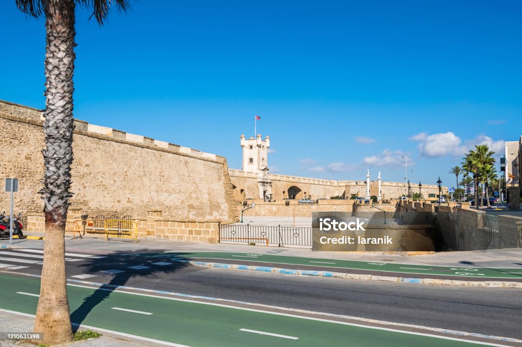 Plaza de la Constitucion with Puertas de Tierra in Cadiz, Spain Plaza de la Constitucion with Puertas de Tierra, a bastion-monument built around remnants of the old defensive wall with the purple flag of its canton at the entrance to the city of Cadiz, Spain Altar Stock Photo