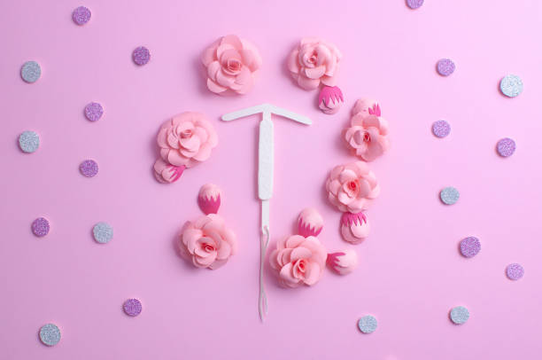 Concept hormonal contraception - pills and IUD. Paper flower, copyspace Concept hormonal contraception - pills, IUD, beautiful shiny tablets on a pink background, with paper flowers. Copy space for text iud stock pictures, royalty-free photos & images