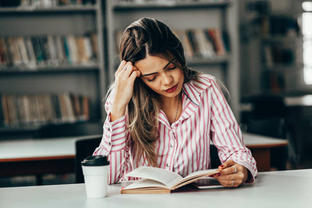 istock Tired woman studying at table in library 1210632950