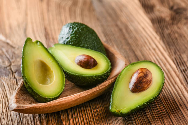 Avocado on old wooden table in bowl. stock photo