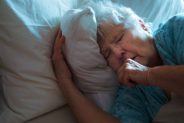 mujer de edad avanzada enferma en la cama tosiendo - cough remedy fotografías e imágenes de stock