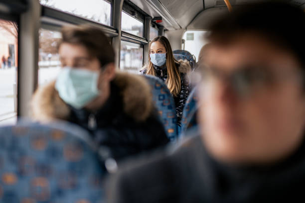 Young girl wearing sterile face mask using a public transport Young girl is wearing sterile face mask because of the new Coronavirus COVID-19. She is sitting on a bus. She is looking outside the window. public transportation photos stock pictures, royalty-free photos & images