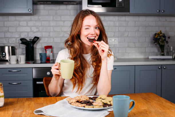 woman eating cookie and drinking milk. - chocolate white chocolate chocolate chip white imagens e fotografias de stock