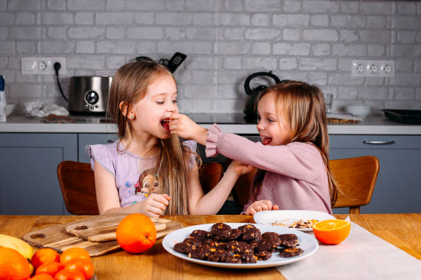 Young girls eating biscuits at home stock photo