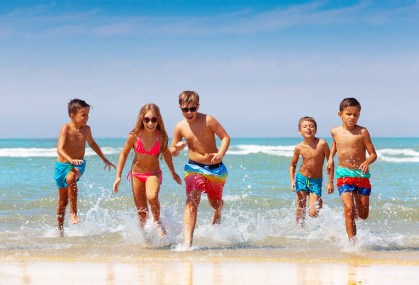 istock Many kids run and splash from sea to the beach 1210659152