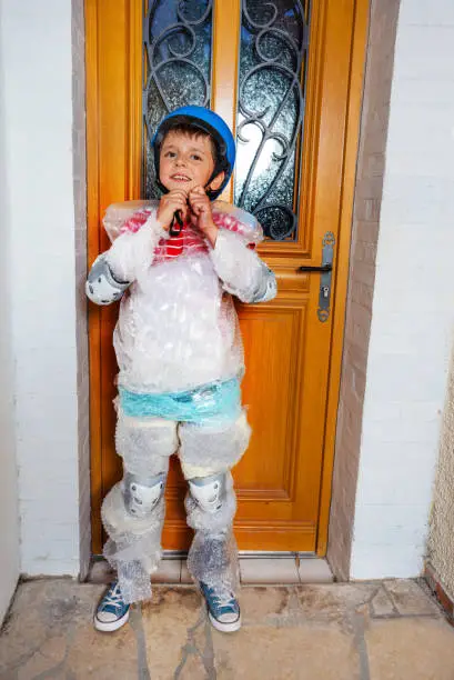 Child fasten helmet wear super safe bubble wrap have overprotective mother standing near home door