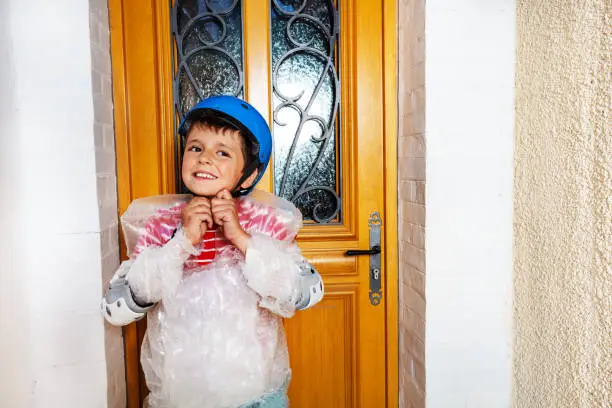 Boy fasten helmet wear super safe bubble wrap have overprotective mother standing near home door