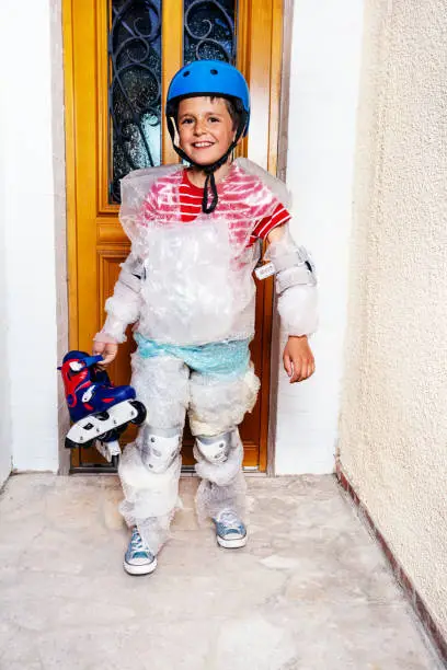 Child with rollerblades ball wear super safe bubble wrap and helmet have overprotective mother standing near home door
