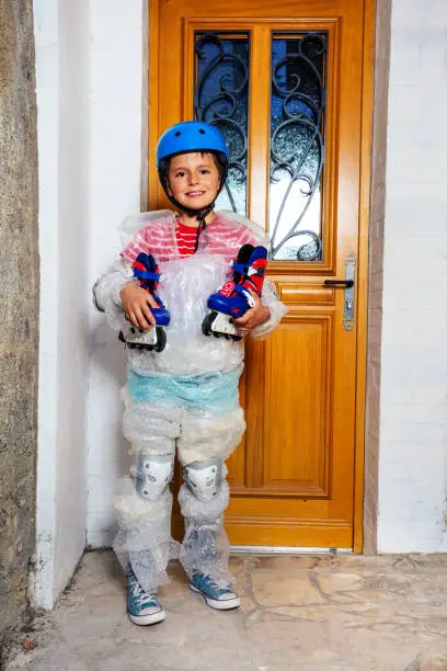 Boy with rollerblades ball wear super safe bubble wrap and helmet have overprotective mother standing near home door