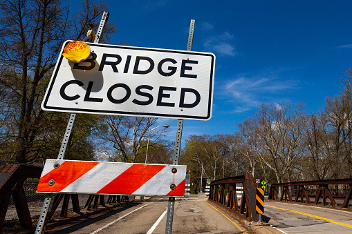 Close photo of a bridge closed sign on USA local road in Pittsburg with construction on background