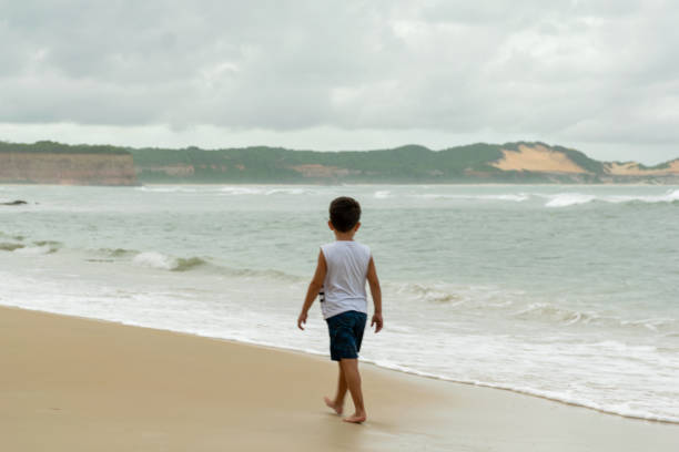 istock 6 year old child walking along Pipa beach on a cloudy day. 1210662167