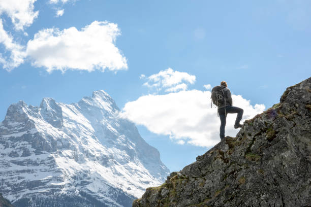 Male hiker climbs ridge crest above mountains