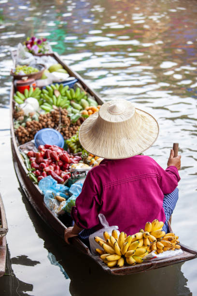 les vendeurs du marché aux fruits tropicaux thaïlandais vendent son produit à partir d’un bateau de canal sur le marché flottant de damnoen saduak. - damnoen saduak floating market photos et images de collection