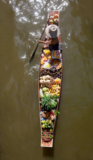 vendeur thaïlandais de marché de fruits tropicaux pagayant son produit d’un bateau de canal, directement au-dessus de la vue, au marché flottant de damnoen saduak. - damnoen saduak floating market photos et images de collection