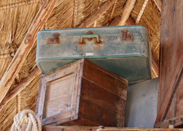 Close up stack of two old vintage antique grunge travel luggage brown leather suitcase trunks isolated over background of brown paper parchment, low angle side view