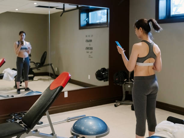 istock asian woman using cellphone in home gym 1210679678
