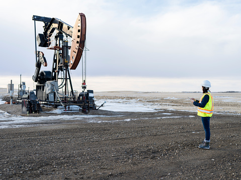 asian female oil worker using tablet pc at oil field of Saskatchewan,Canada.