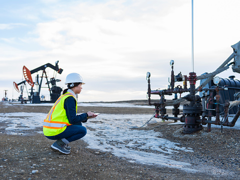 asian female oil worker using tablet pc at oil field of Saskatchewan,Canada.