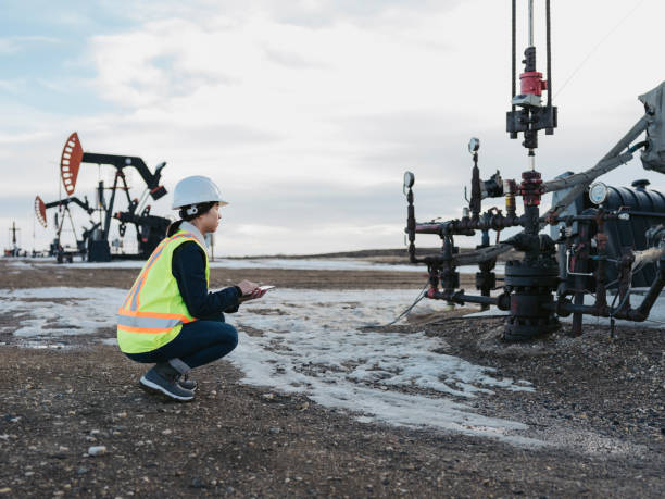 asian female oil worker using tablet pc asian female oil worker using tablet pc at oil field of Saskatchewan,Canada. oil pump petroleum equipment development stock pictures, royalty-free photos & images