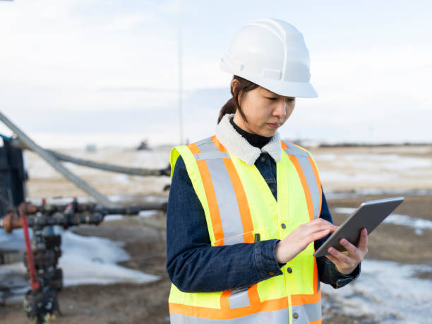 азиатская женщина-нефтяник с помощью планшетного пк - oil industry digital tablet manual worker mining стоковые фото и изображения