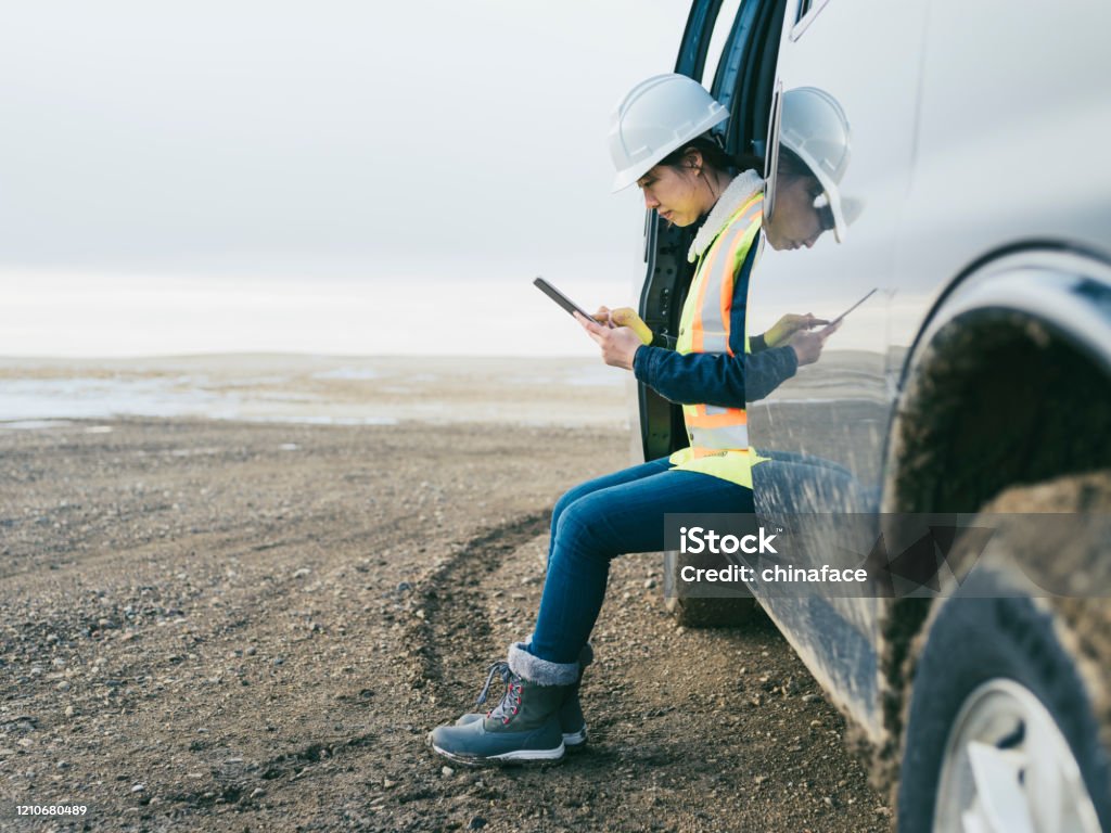female oil Worker using  tablet pc female oil worker working at oil field, Saskatchewan, Canada. Mining - Natural Resources Stock Photo