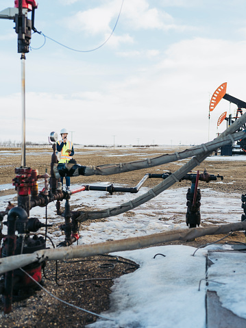 Female Oil Worker working at oil field with talkie, saskatchewan, canada.