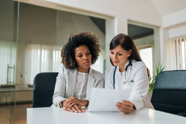 General practitioner showing test results to a charming mixed race woman. General practitioner showing test results to a charming mixed race woman. healthcare management stock pictures, royalty-free photos & images