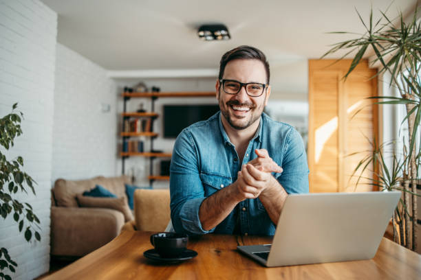 Portrait of a successful entrepreneur at cozy home office, smiling at camera. Portrait of a successful entrepreneur at cozy home office, smiling at camera. business lifestyle stock pictures, royalty-free photos & images