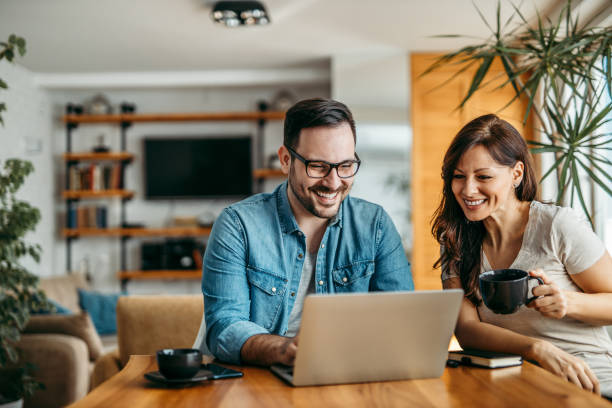 smiling couple relaxing at home with laptop, portrait. - couple home interior laptop computer imagens e fotografias de stock