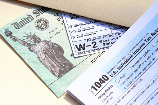 Tax forms with United States Treasury check. IRS tax forms 1040 and W-2. Tax preparation concept. Treasury check represents a tax refund.