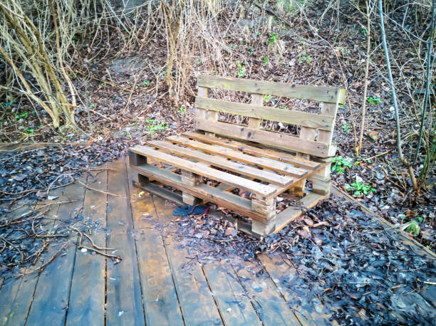 wooden table, bench made of wooden pallets. Rustic, self-made benches and a table made of euro pallets in front of a wooden wall. Rustic Wooden Furniture in a forest