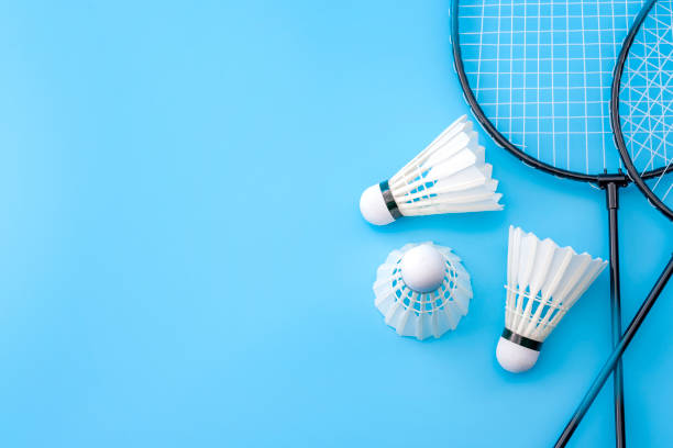 leistungssport und hohe leistung im turnier match konzeption idee mit badmintonschläger und shuttlecock (birdie) isoliert auf blauem court hintergrund mit kopierraum - badmintonschläger stock-fotos und bilder